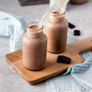 Chocolate Milk two small glass milk jars filled with chocolate milk on cutting board