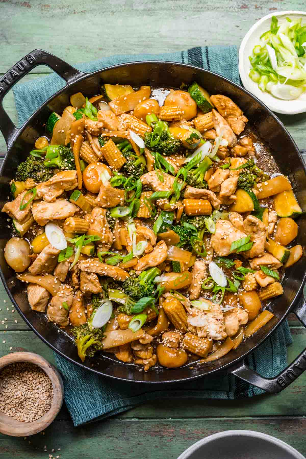 Chop Suey finished dish in skillet, blue gray background and ingredient decorations