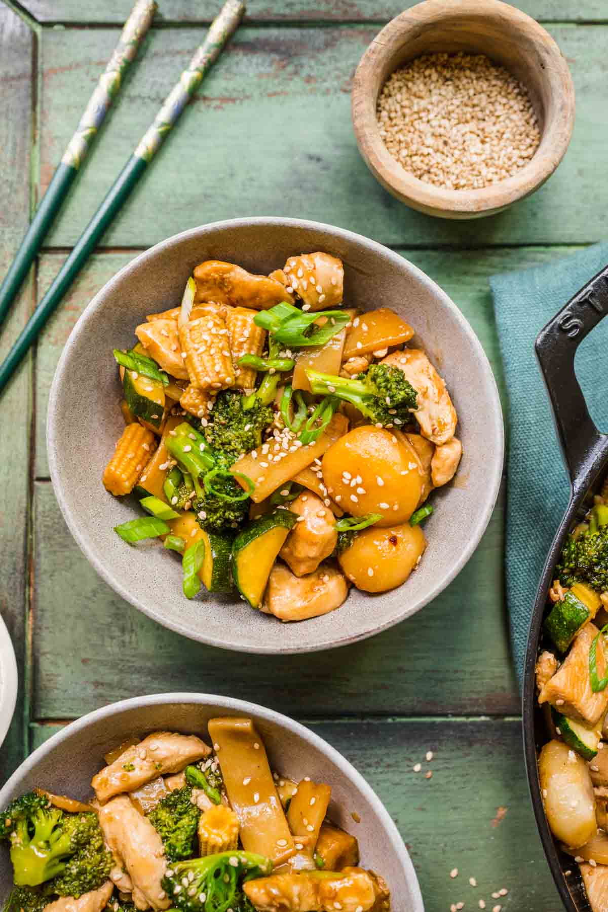 Chop Suey finished dish in bowls with chopsticks off to side, blue background and ingredient decorations