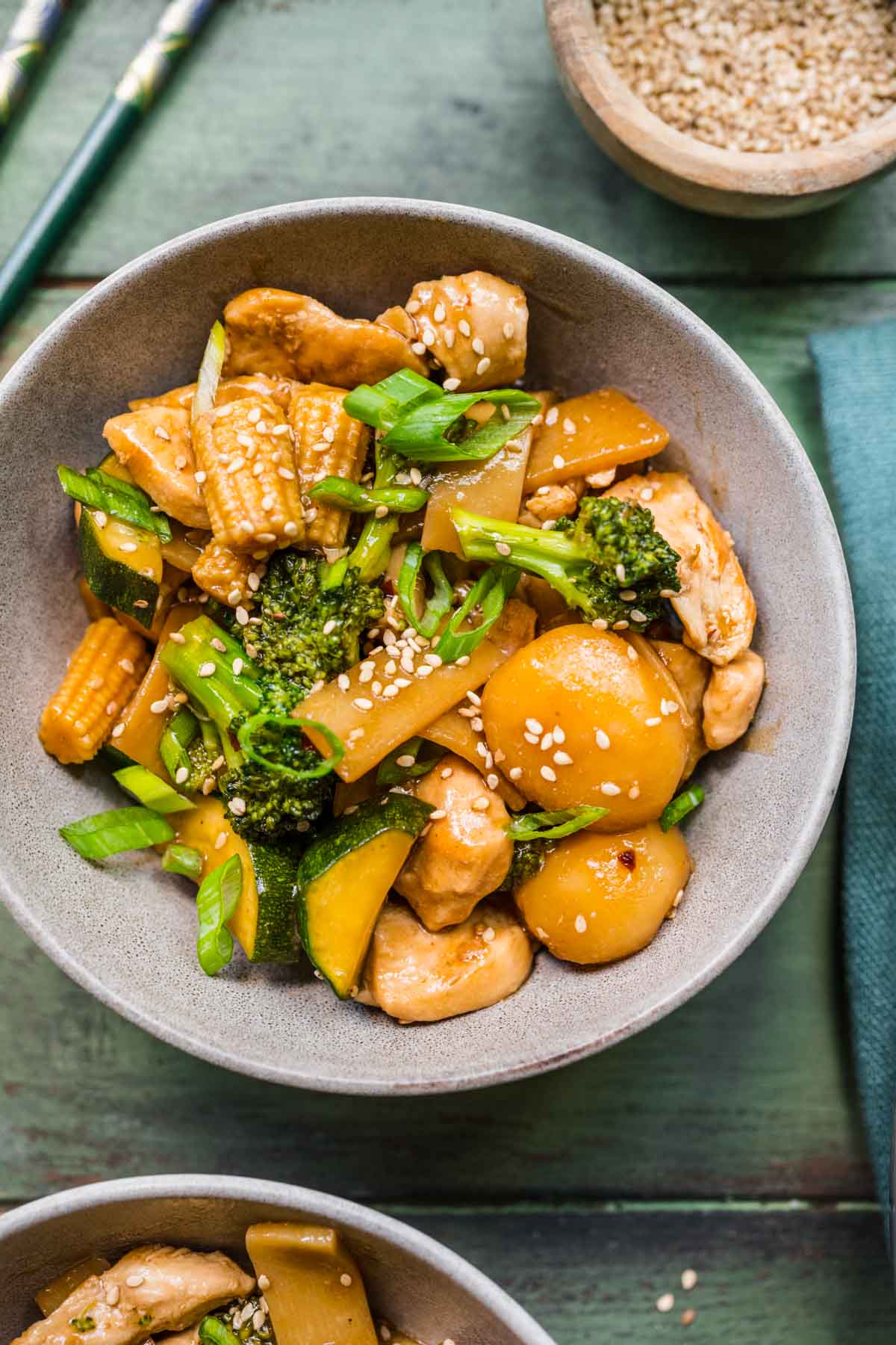 Chop Suey finished dish in bowl with chopsticks off to side, blue background and ingredient decorations