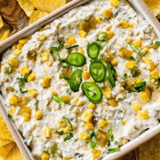 Finished dip in dish topped with sliced jalapenos, surrounded by chips