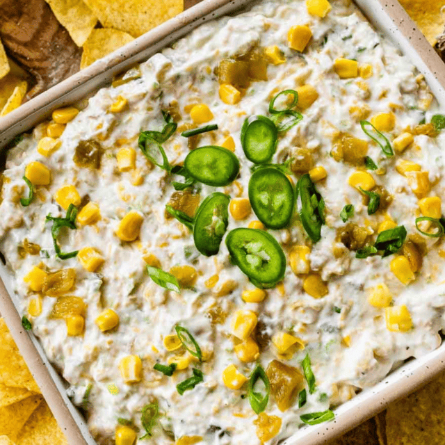 Finished dip in dish topped with sliced jalapenos, surrounded by chips