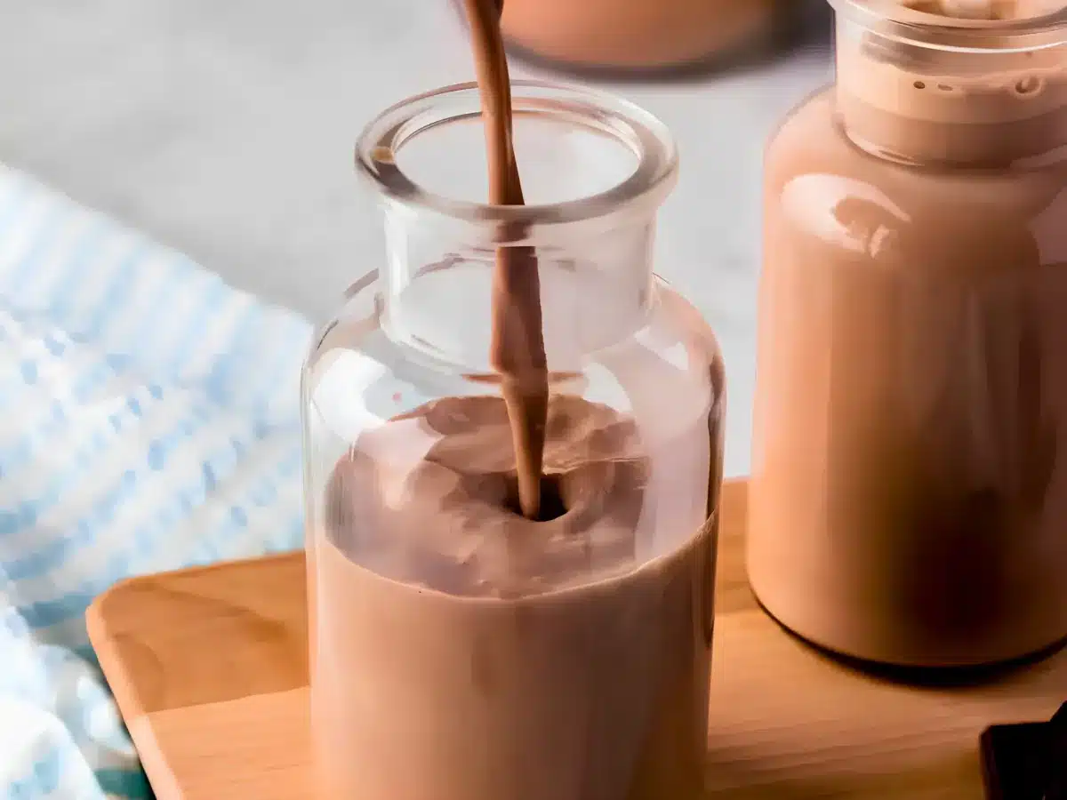 brown liquid being poured into a tall glass bottle