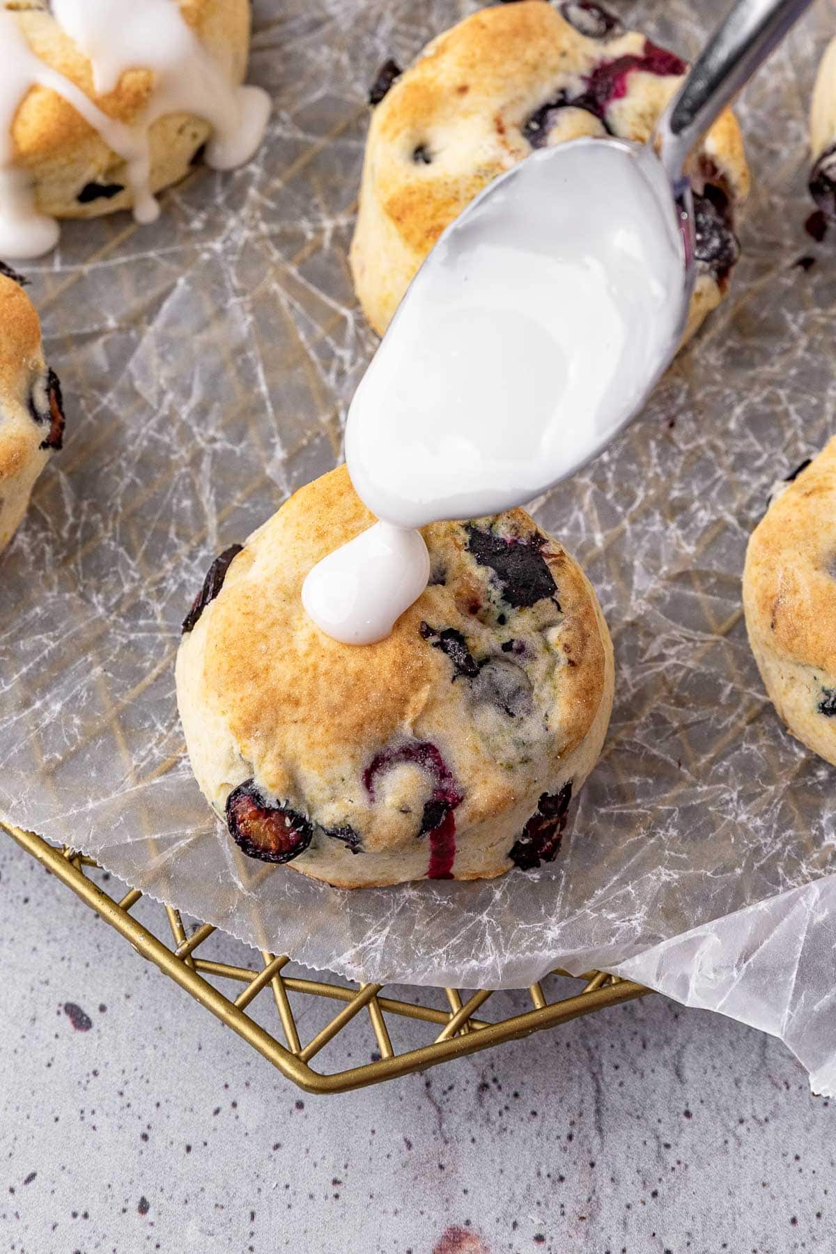 Lemon Blueberry Biscuits spooning glaze over baked biscuits