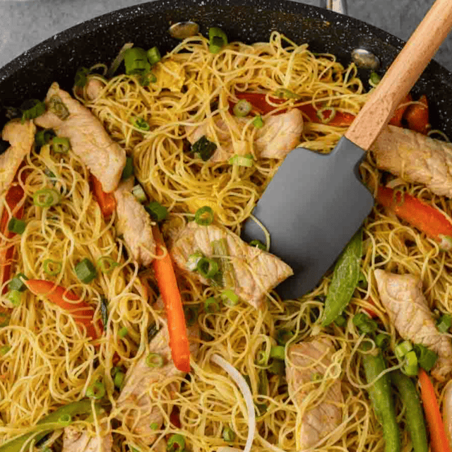 noodle dish in pan cooking with spatula
