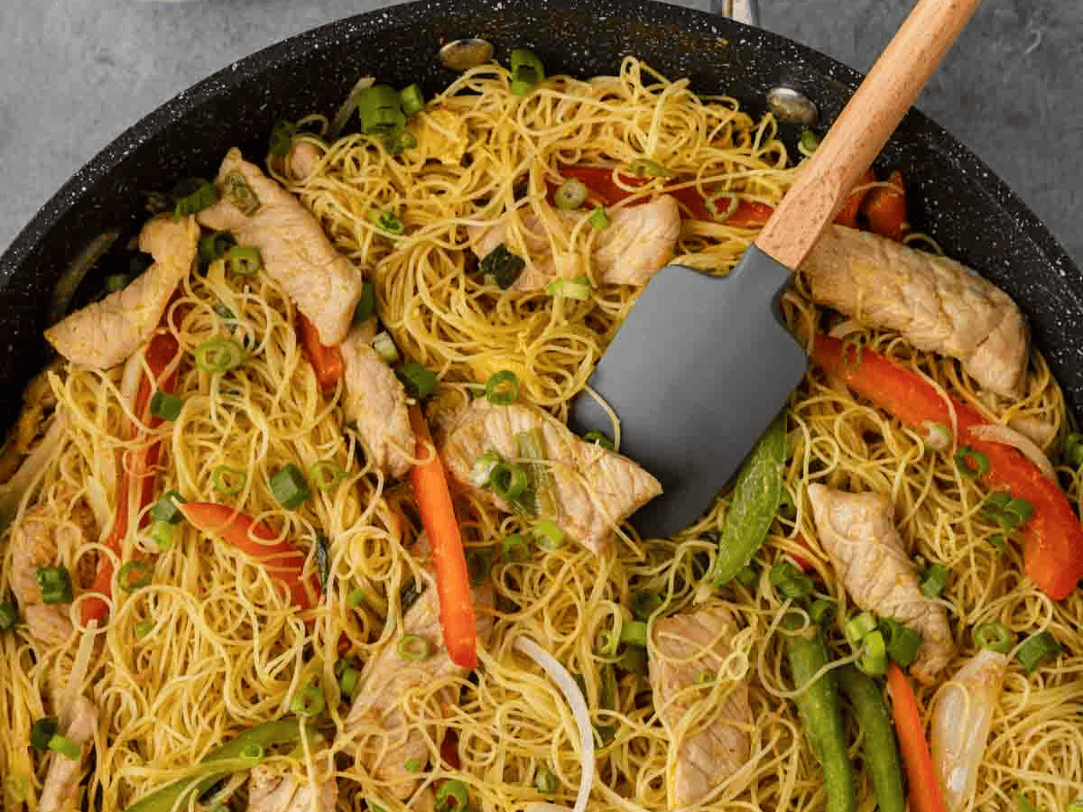 noodle dish in pan cooking with spatula