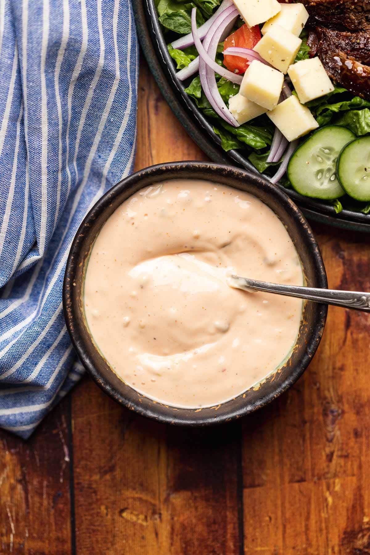 Steak Salad dressing in bowl with spoon and salad off to side