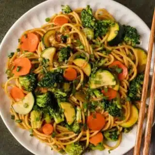 Noodles and stir fry served on plate with chop sticks