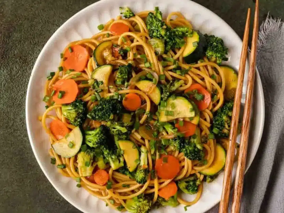 Noodles and stir fry served on plate with chop sticks