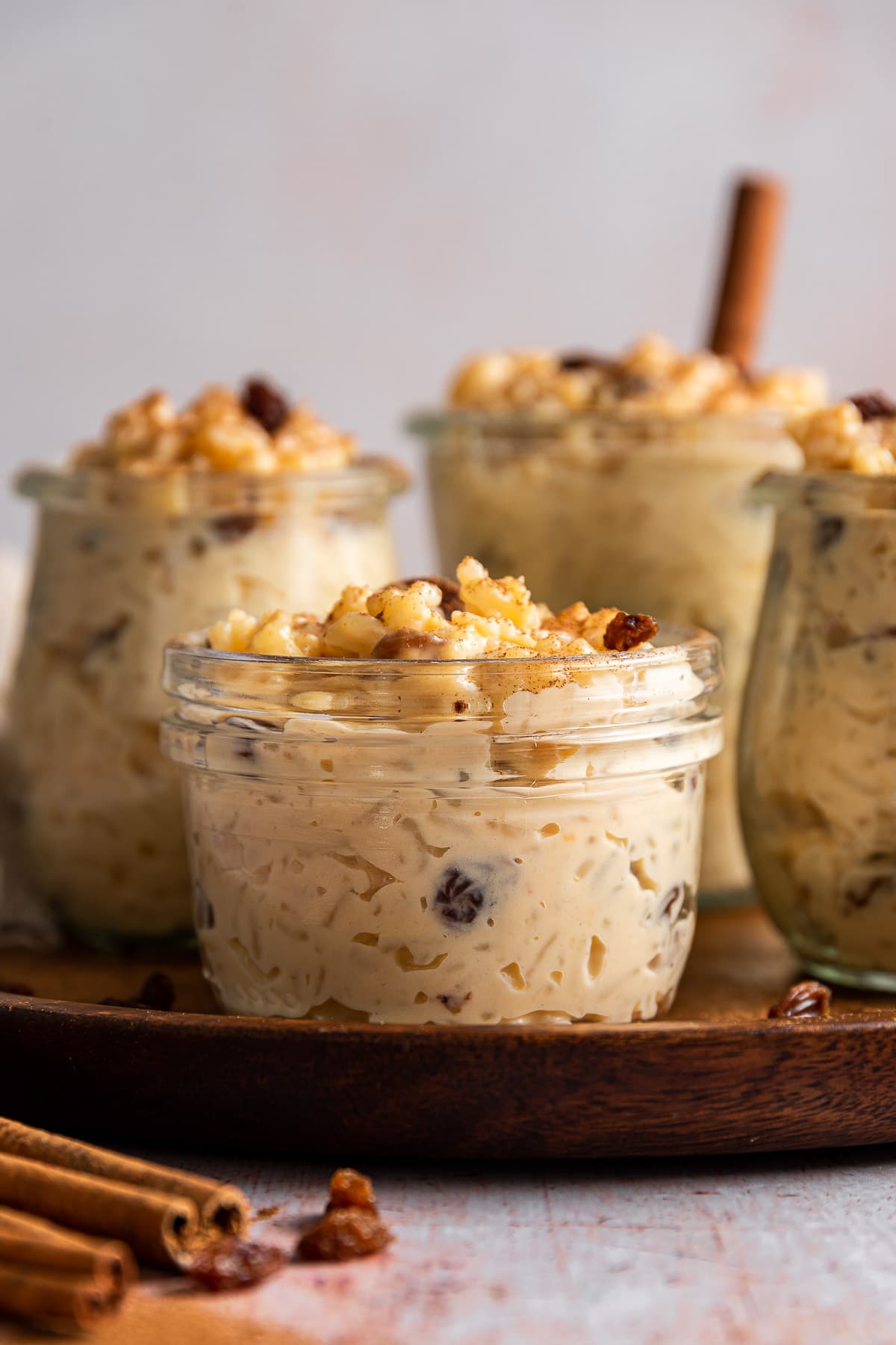 Arroz con Leche finished pudding in jars on tray with cinnamon sticks