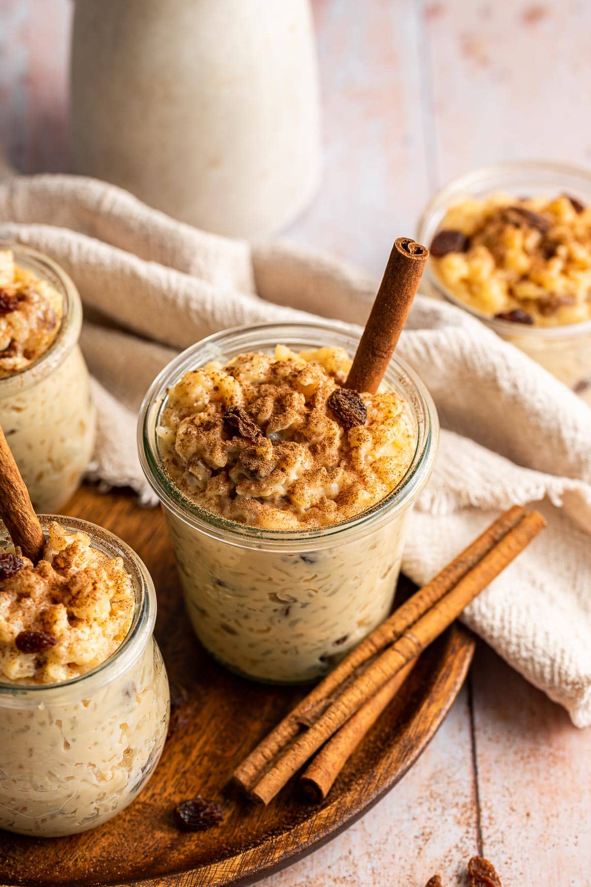 Arroz con Leche finished pudding in jars on tray with cinnamon sticks