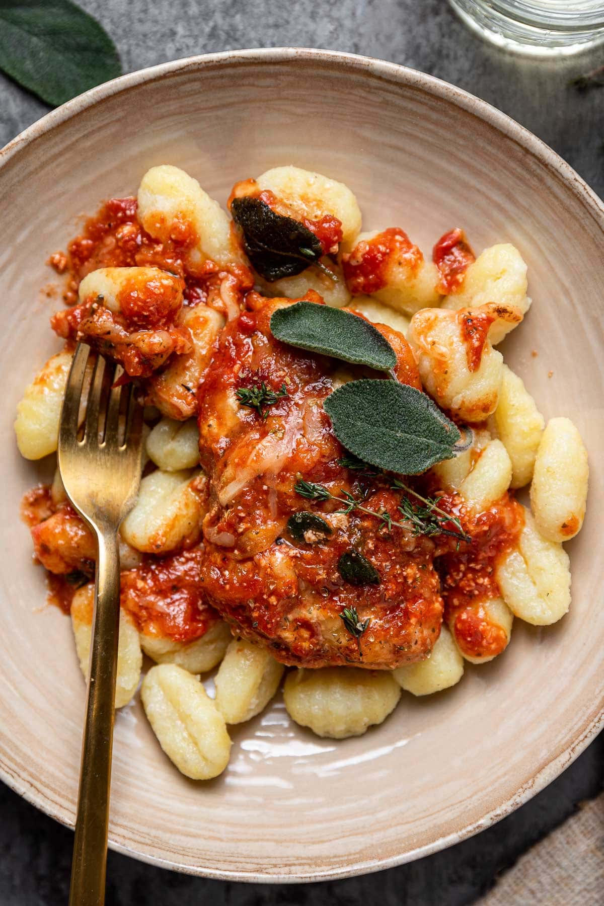 Baked Cheesy Italian Chicken plated over gnocchi with fork holding up bite