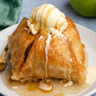 Apple dumpling topped with sauce and vanilla ice cream.