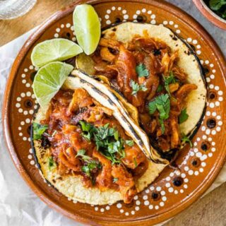 2 tacos on a plate with wedges of Lime
