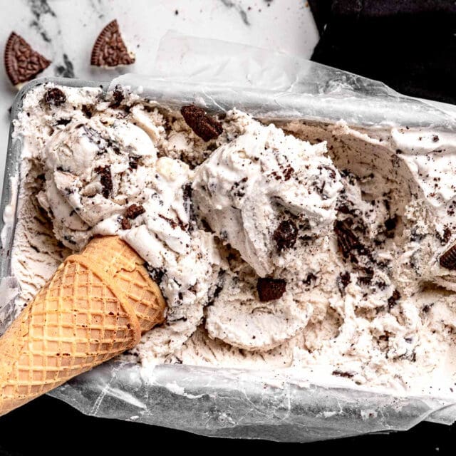 Scooped ice cream in cone laying on ice cream in pan