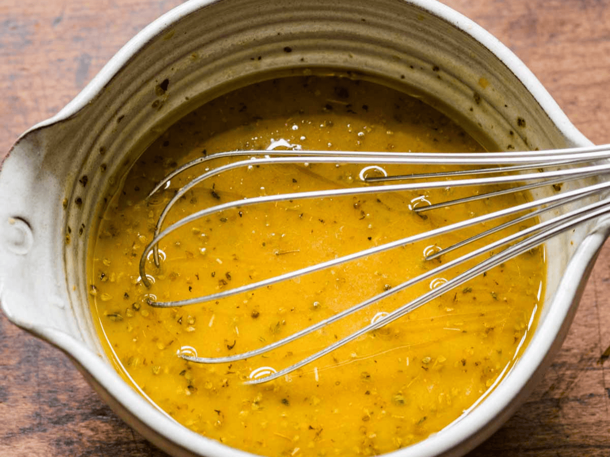 Homemade dressing in a bowl with whisk.