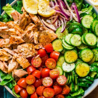 Bowl of green salad with fish and veggies.