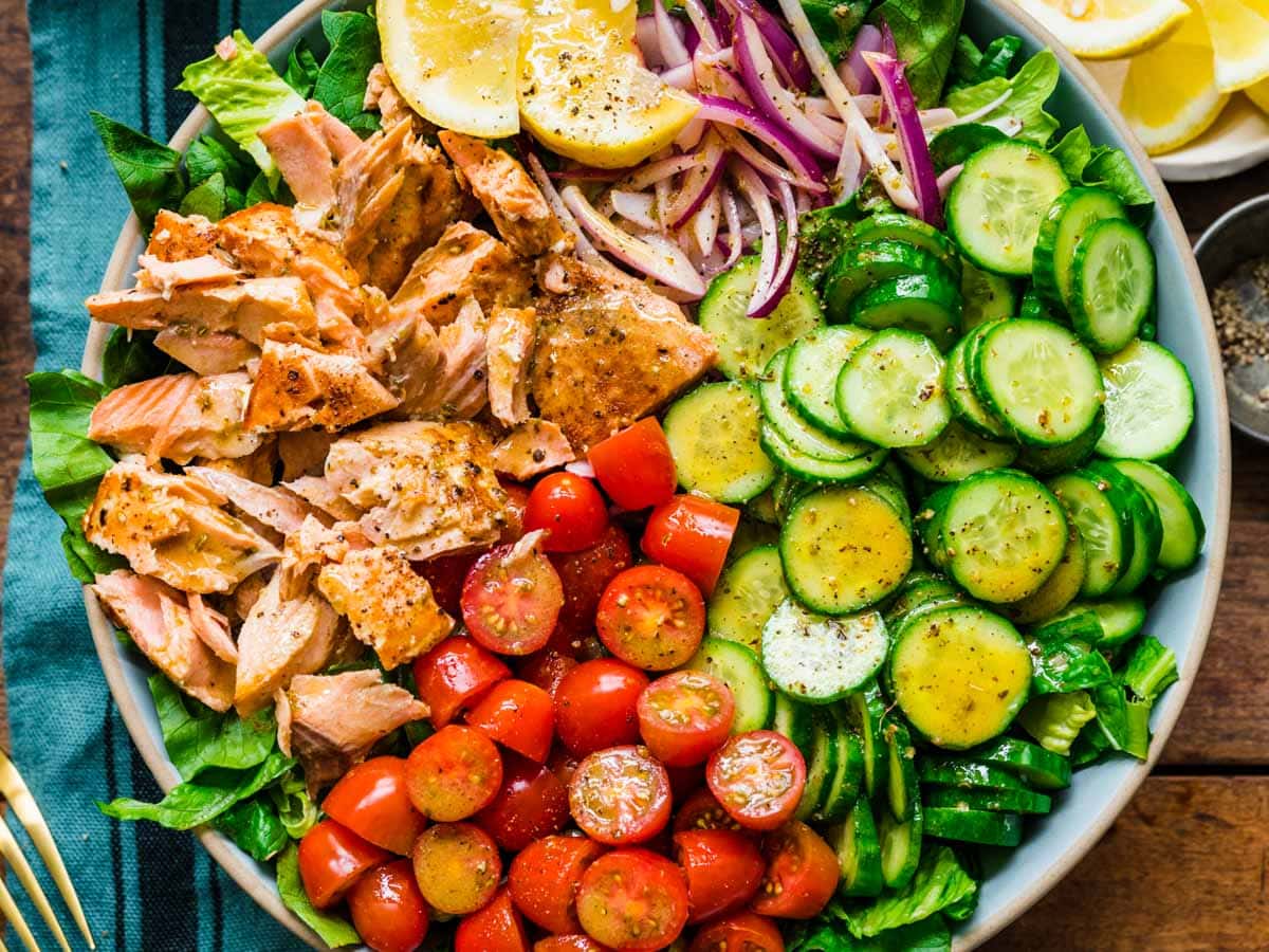 Bowl of green salad with fish and veggies.