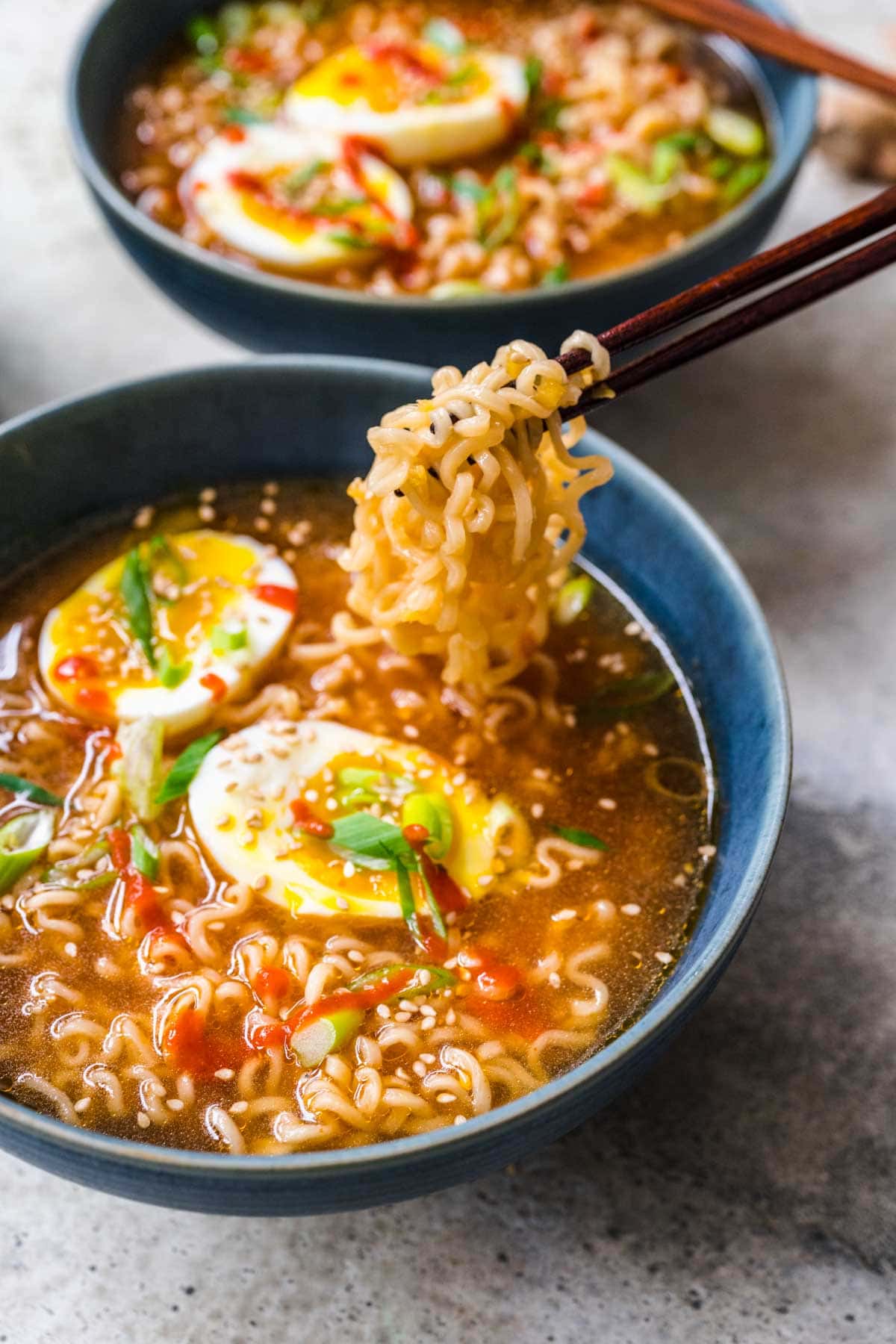 Spicy Ramen finished in bowl with toppings and chopsticks holding noodles over bowl