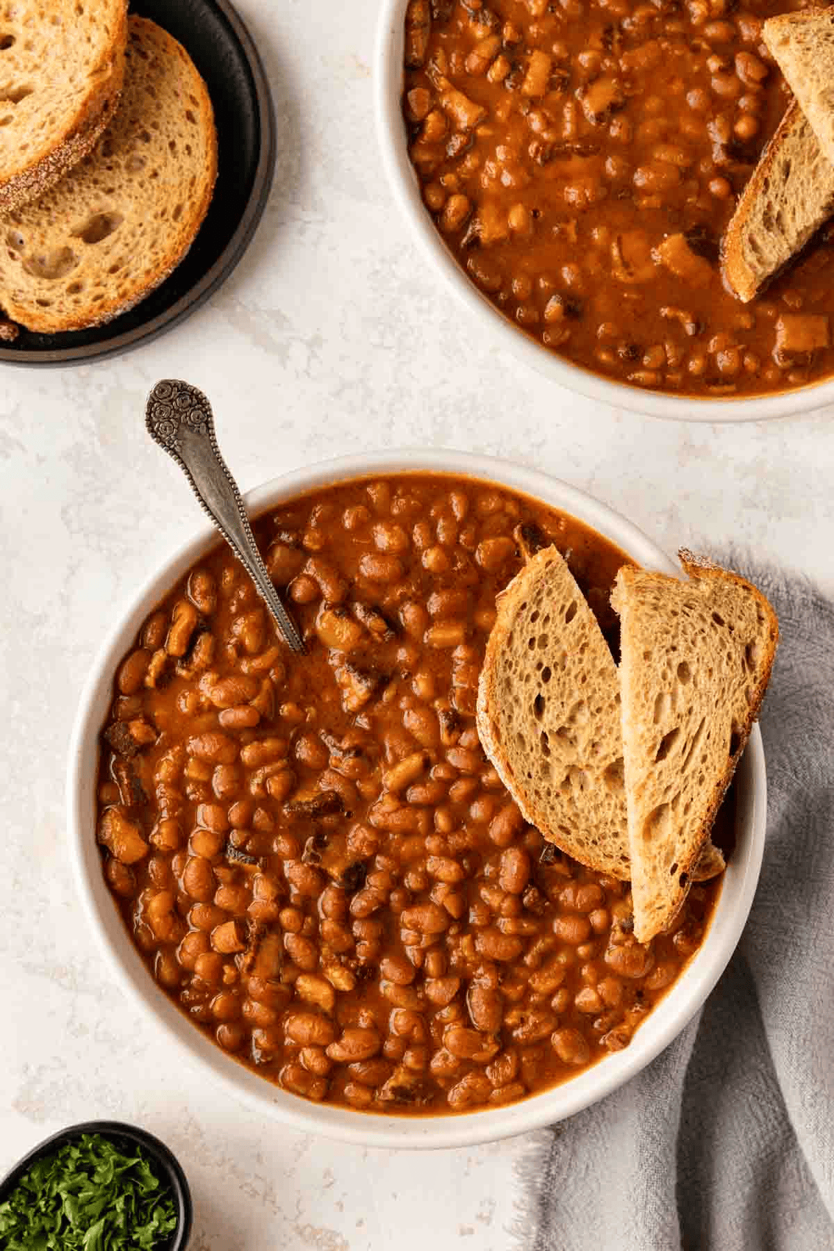 White bowl of homemade beans with bread slices over top
