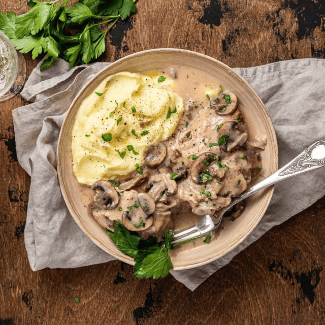 plated pork covered in mushroom gravy served with mashed potatoes