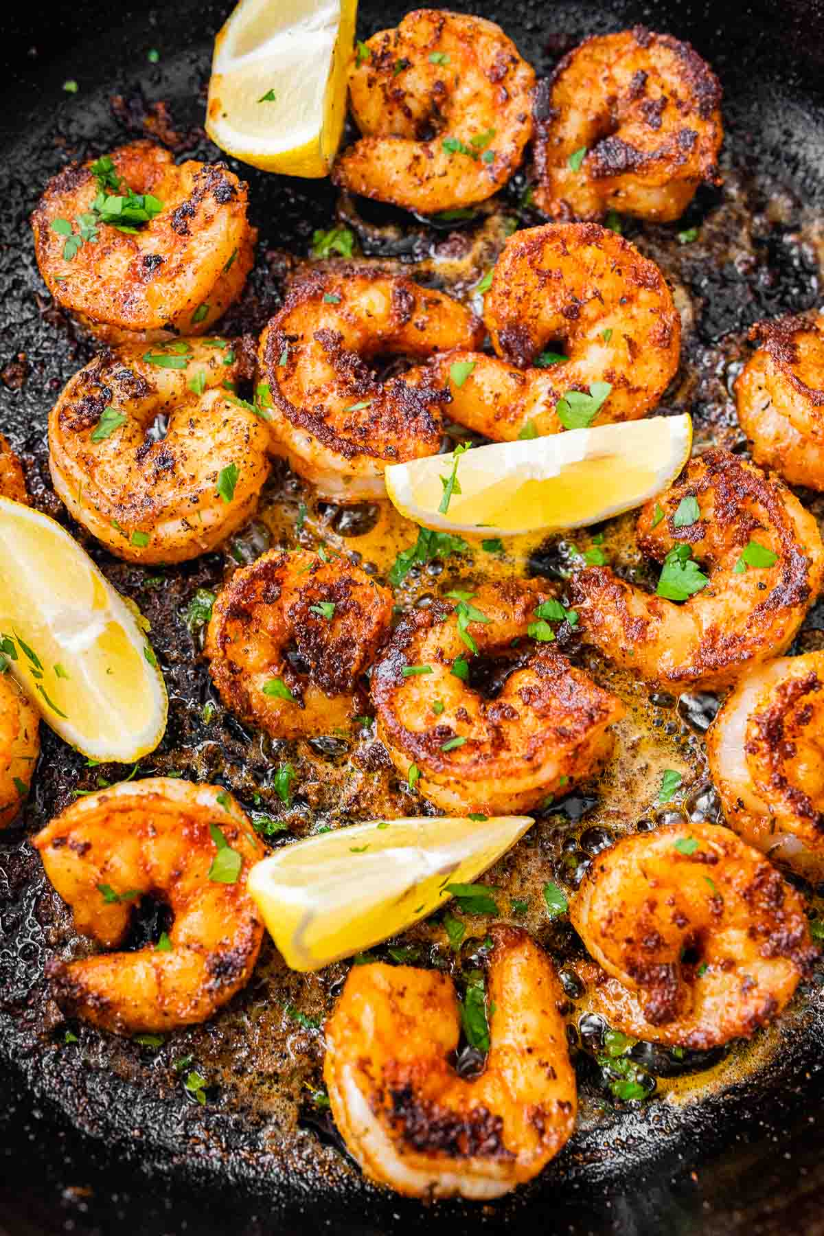 Cajun Shrimp cooked and garnished shrimp in pan with lemon wedges