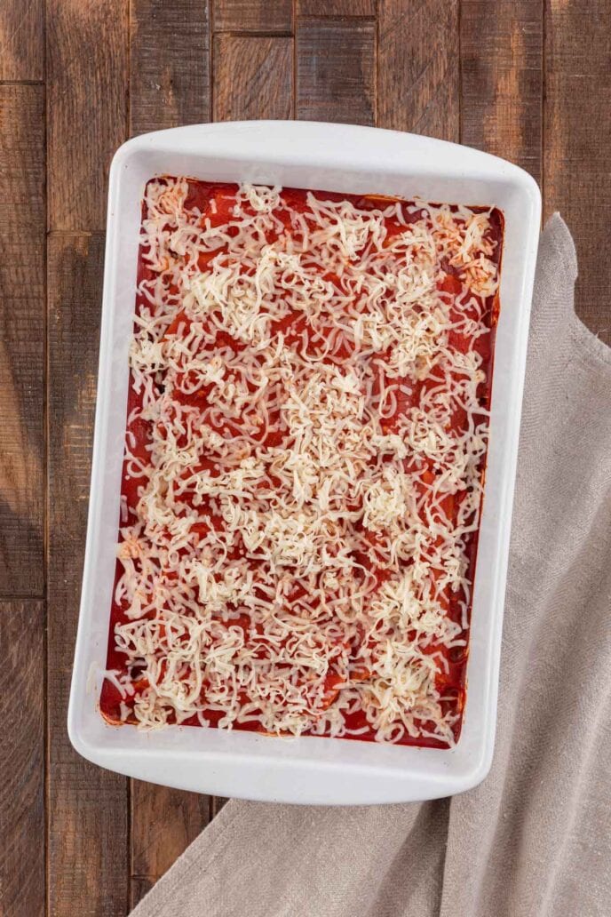 Cheesy Sausage Manicotti in baking dish topped with sauce and cheese