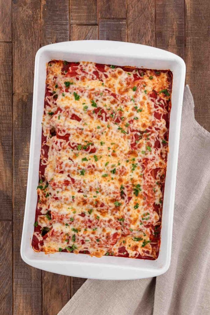 Cheesy Sausage Manicotti in baking dish topped with sauce and cheese fully baked