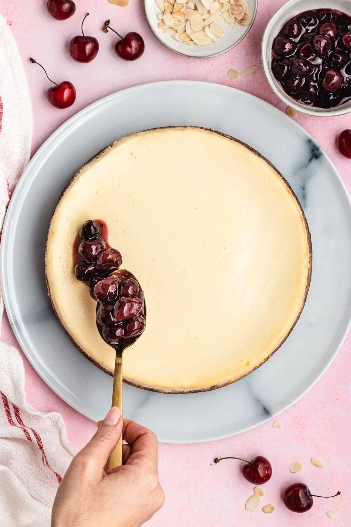 Cherry Cheesecake adding cherry topping to baked cheesecake on cake plate