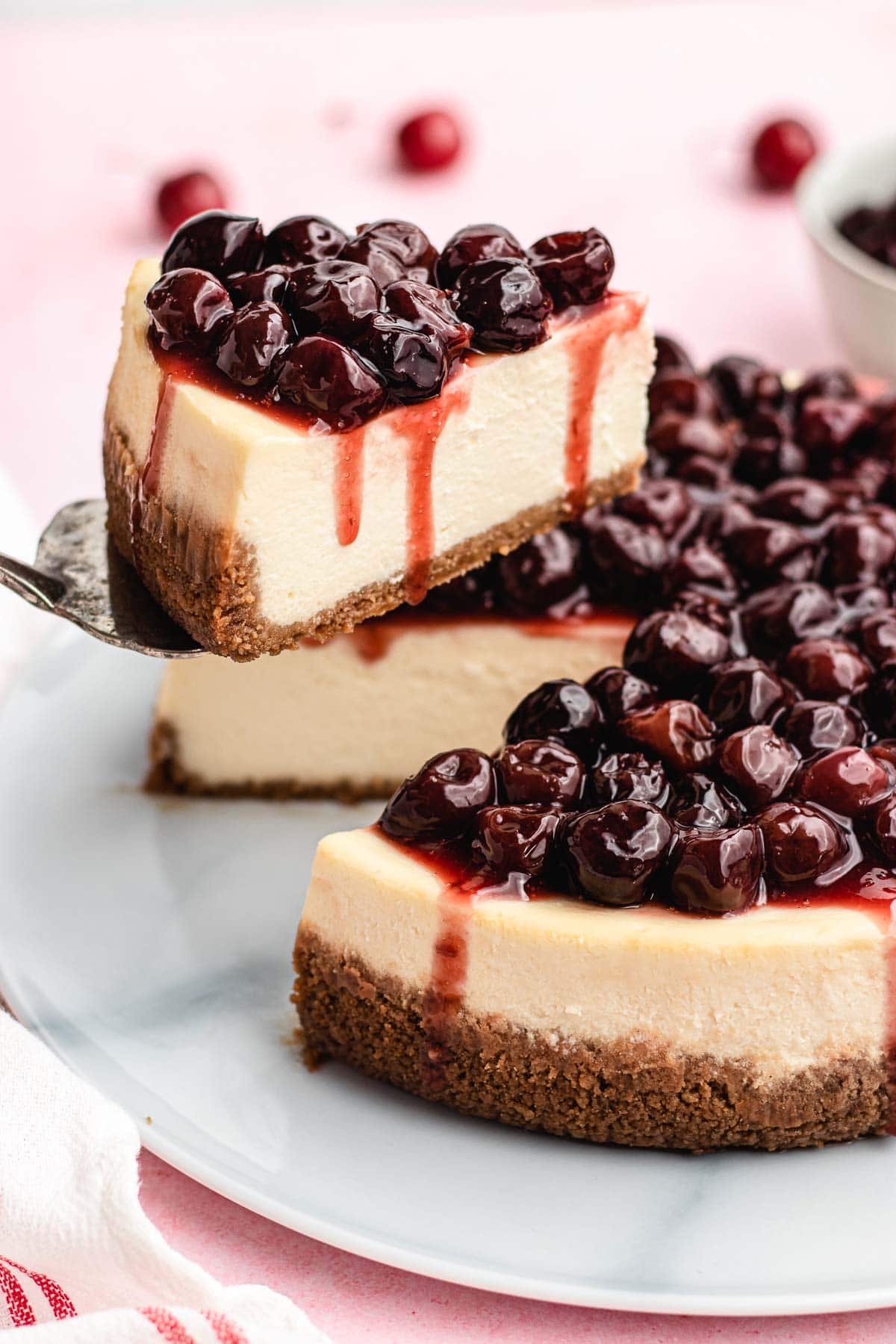 Cherry Cheesecake baked with topping on plate with slice on cake server