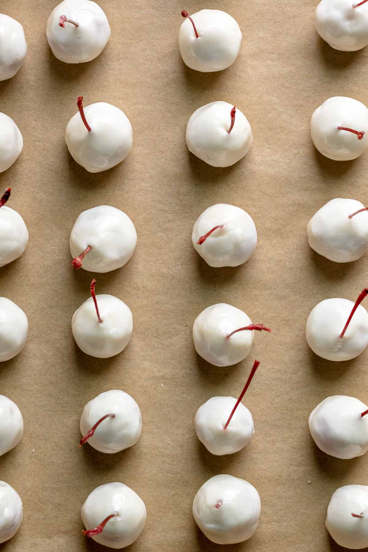 Chocolate Covered Cherry Cordials cherries covered in fondant on parchment paper.