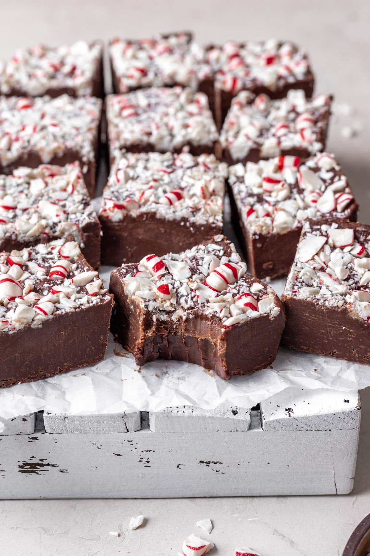 Chocolate Peppermint Fudge finished fudge cut into squares in single layer with bite taking out of one square