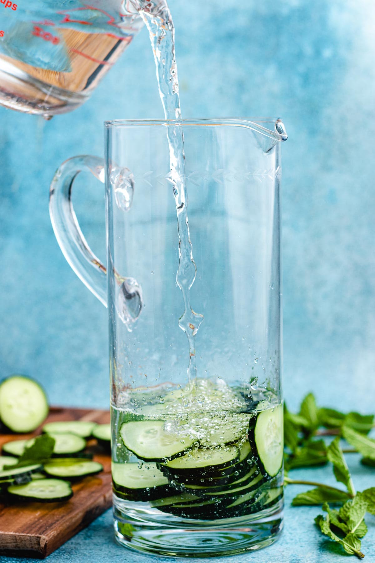 Cucumber Water cucumber slices in bottom of pitcher and pouring water over them