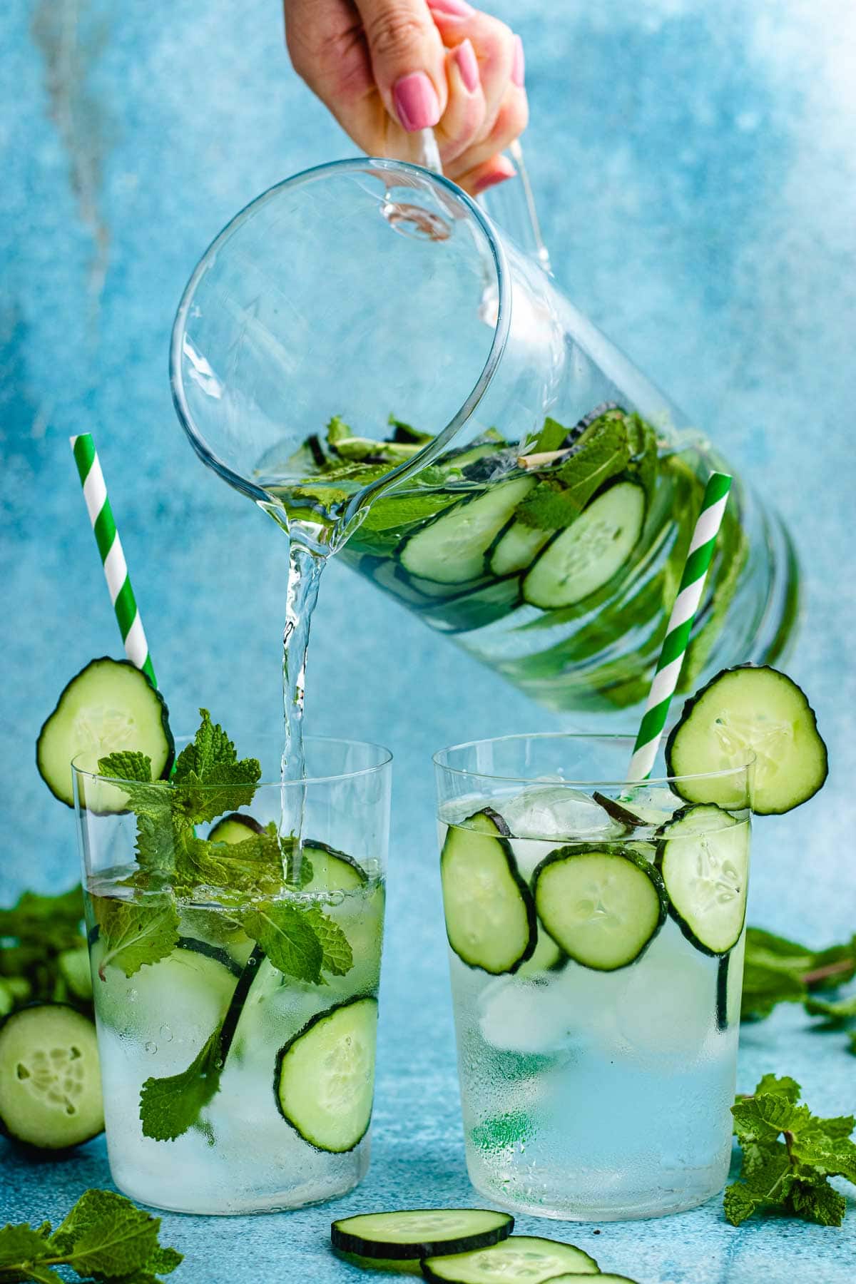 Cucumber Water pouring water in glasses with cucumber slices, with and without mint plus straws and ice