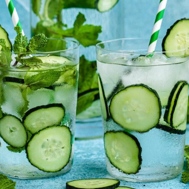 Two water glasses with cucumber, one with mint