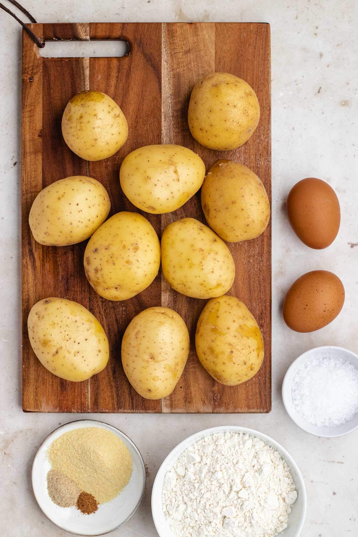 Potato Gnocchi ingredients separated in bowls and raw potatoes on cutting board