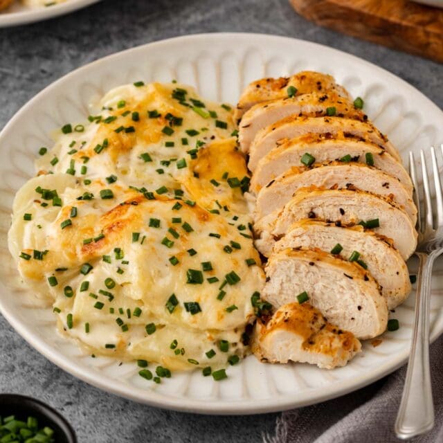 Potato Gratin Dauphinois plated with sliced chicken breast.