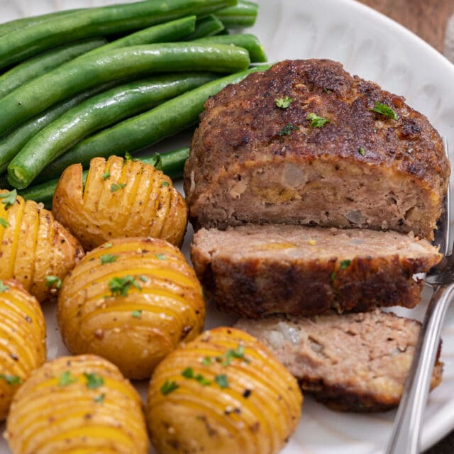 Chopped Steak cooked steak sliced on plate with potatoes and green beans