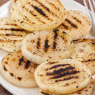 Grilled onions on serving plate with fork.