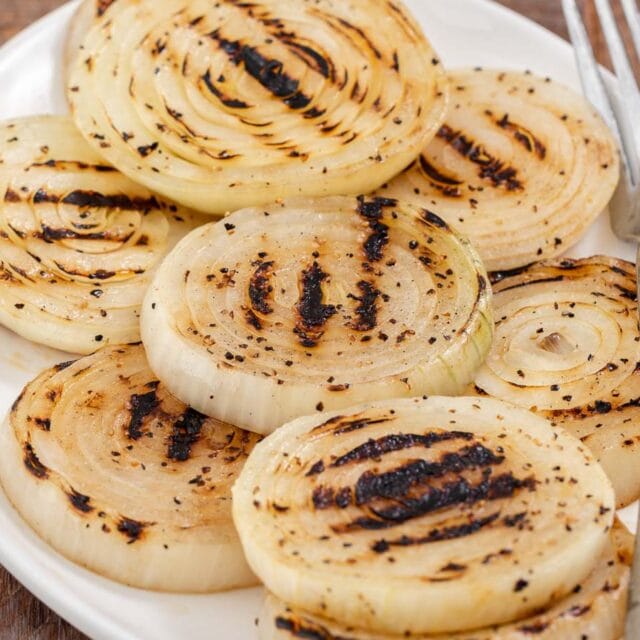 Grilled onions on serving plate with fork.
