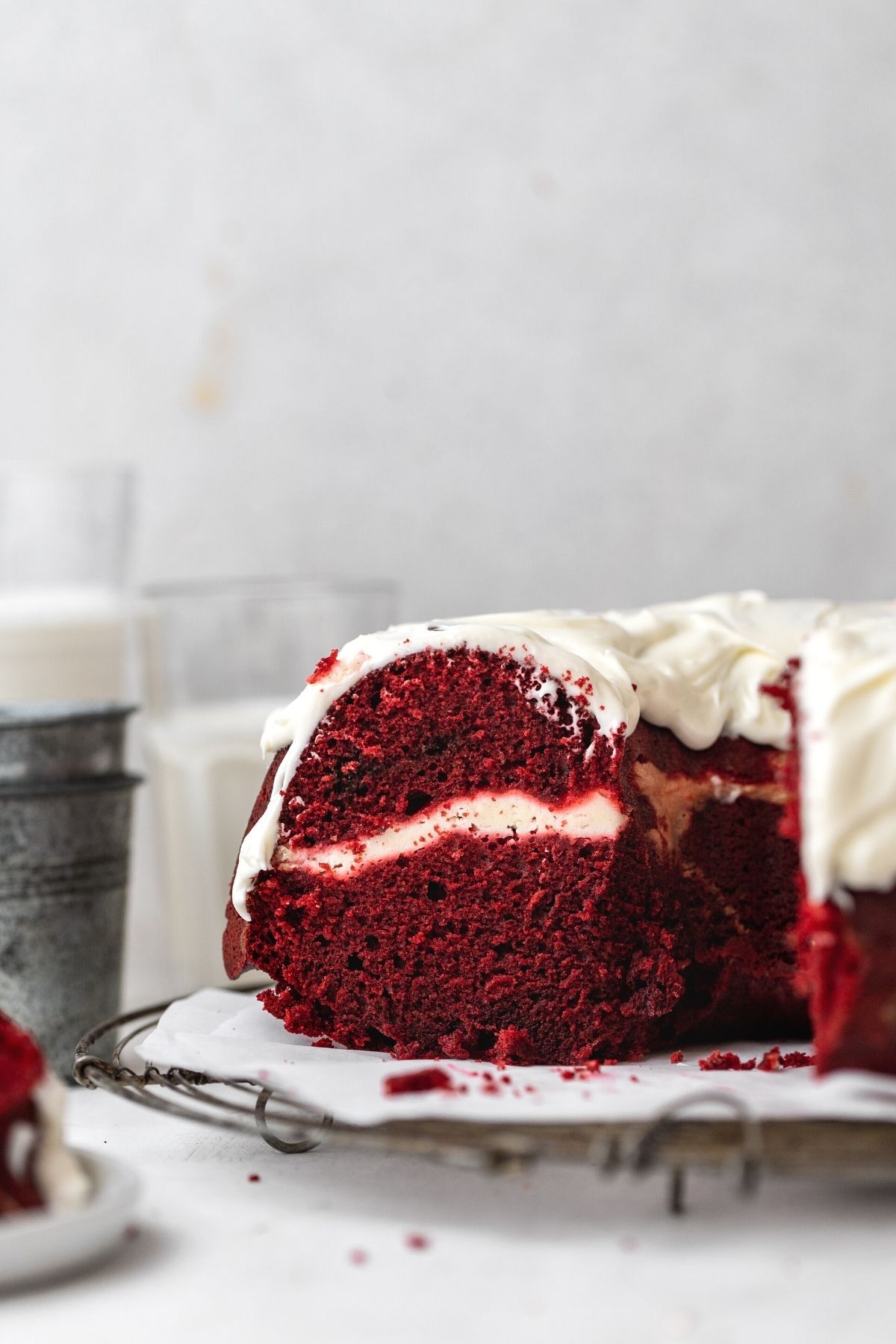 Red Velvet Cheesecake Bundt Cake frosted cake on cake plate with slice removed