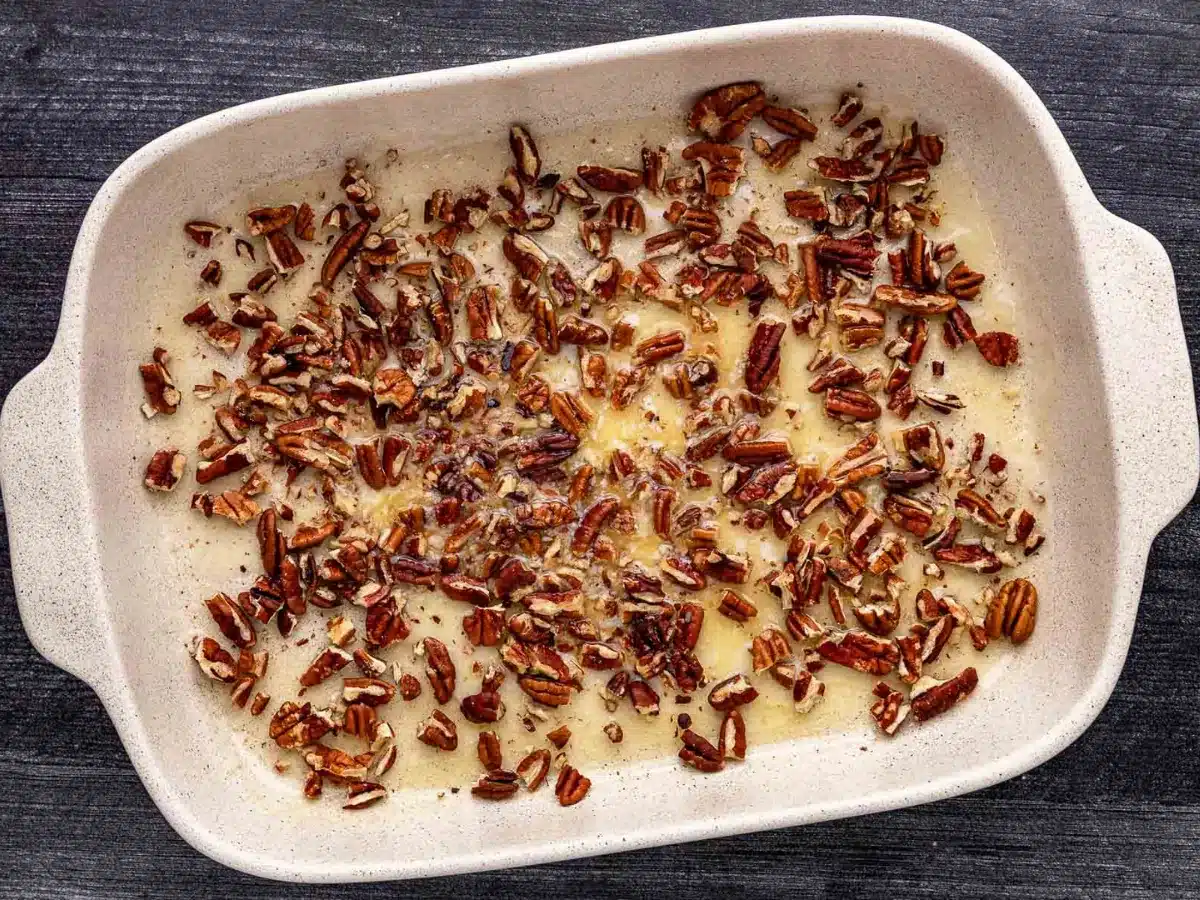 adding butter and nuts to the bottom of the pan 