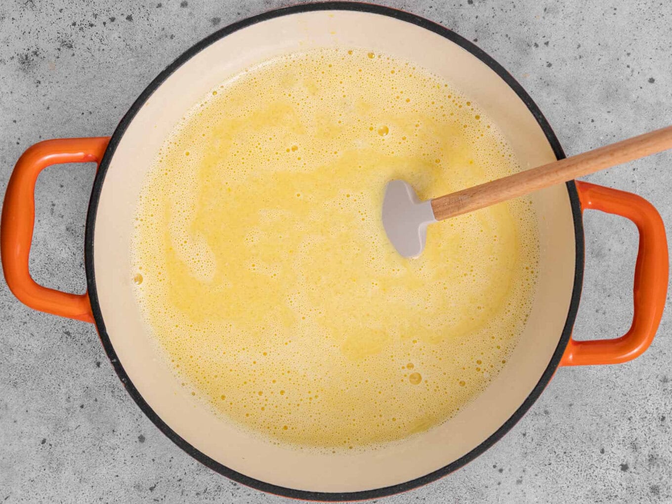 Mixing egg and milk mixture in pot with spatula