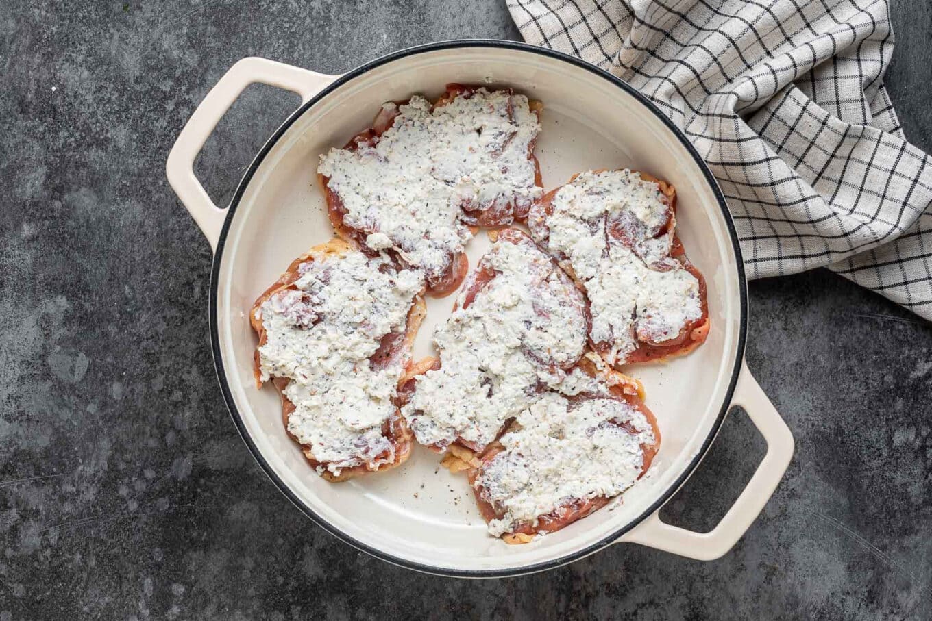 raw boneless chicken thighs covered in ricotta mixture in Dutch oven