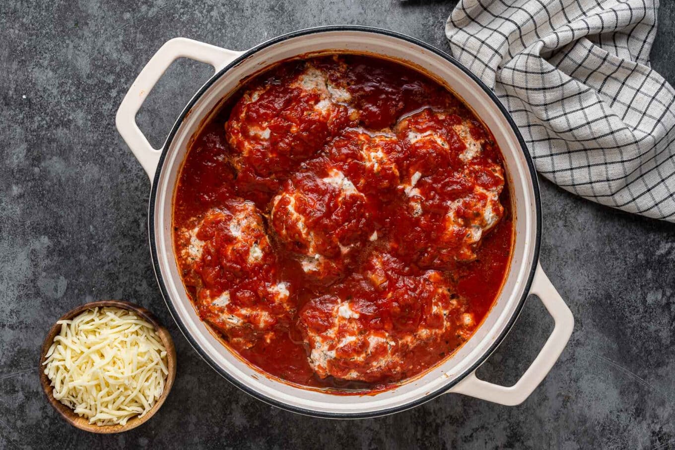 cooked chicken thighs in sauce before adding shredded cheese in Dutch oven