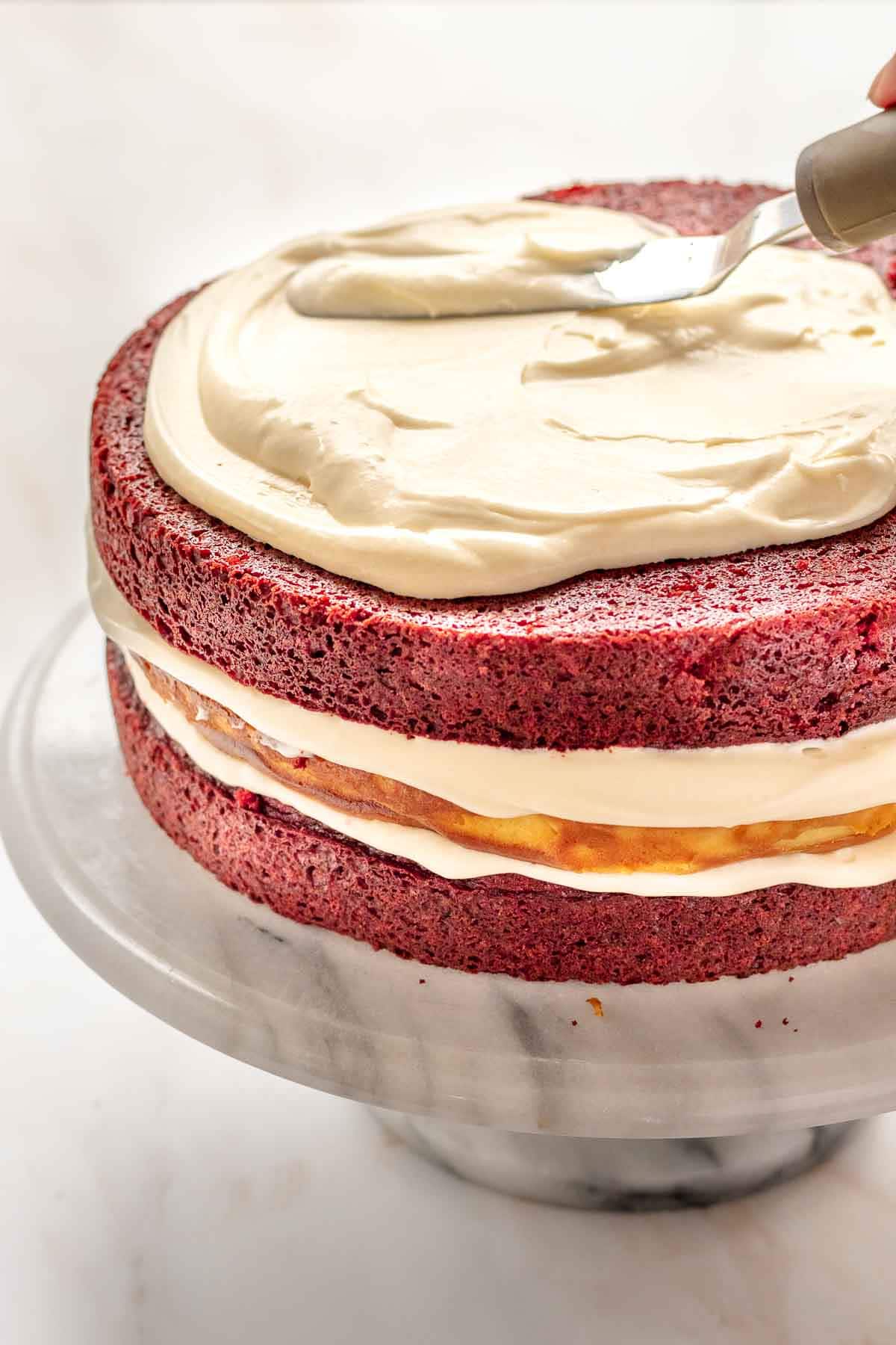 Red Velvet Cheesecake Cake frosting spread on top layer of assembled naked cake