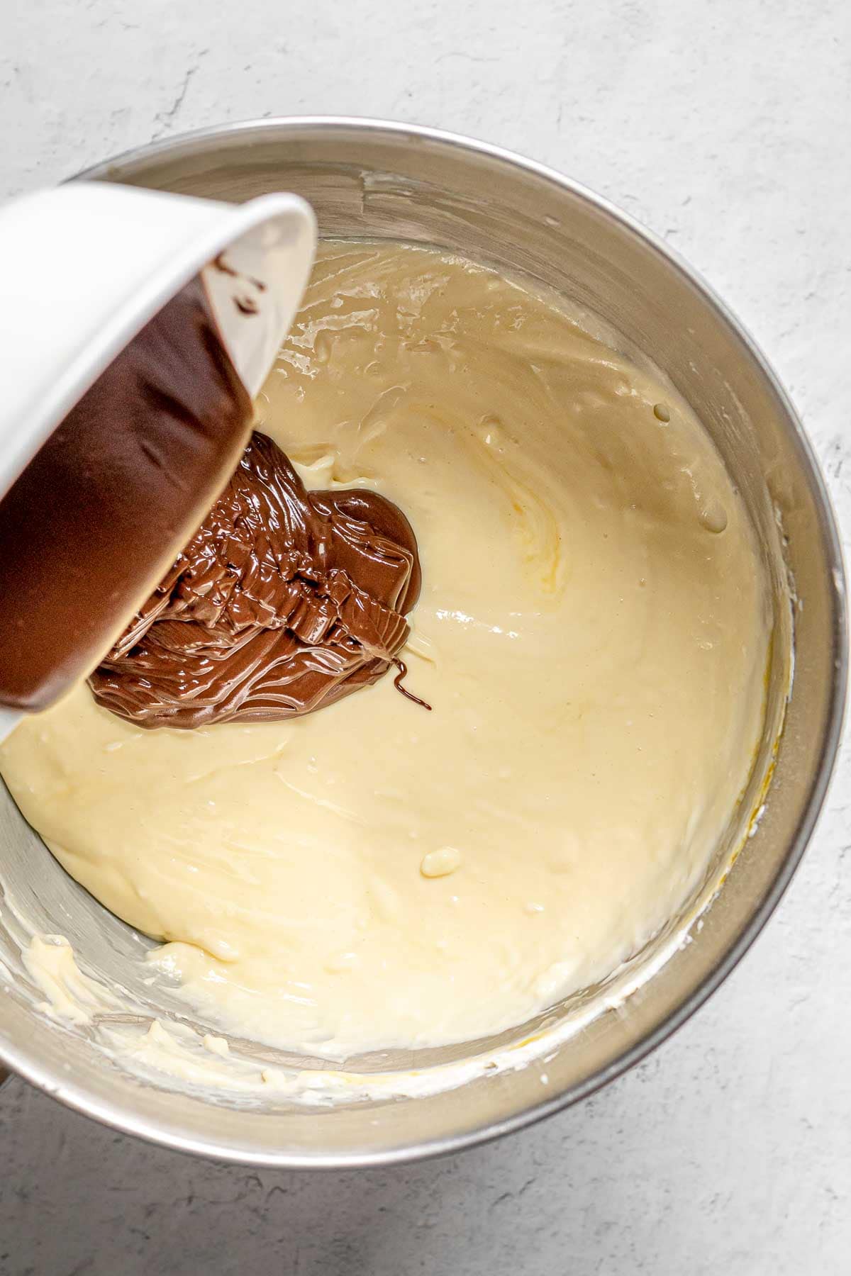 Black Forest Cheesecake adding chocolate to cheesecake batter in bowl