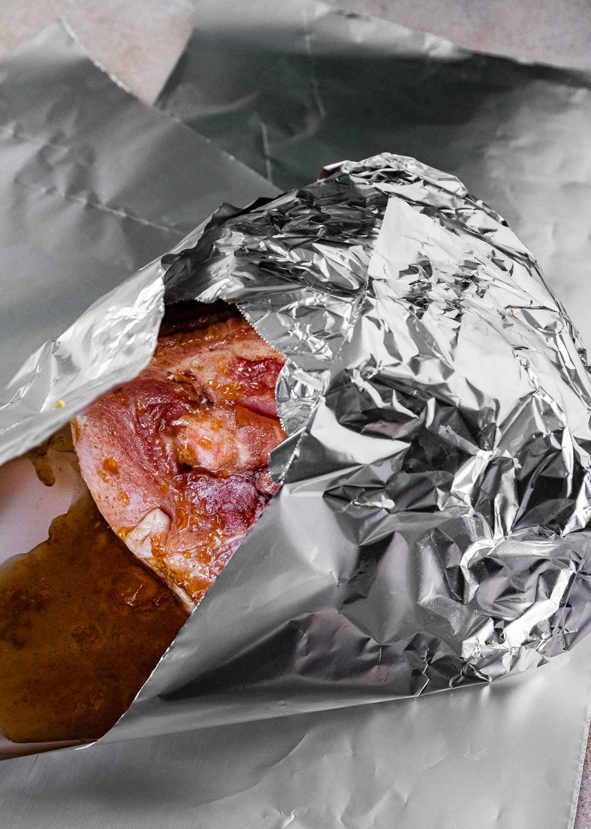 Brown Sugar Peach Baked Ham sauce being wrapped in foil