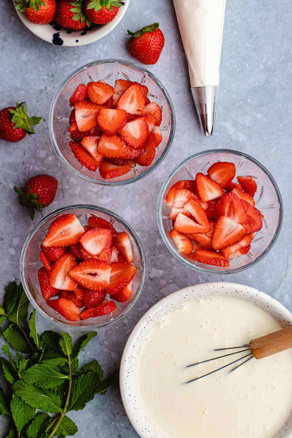Fresas con Crema strawberries in bowls next to cream in mixing bowl