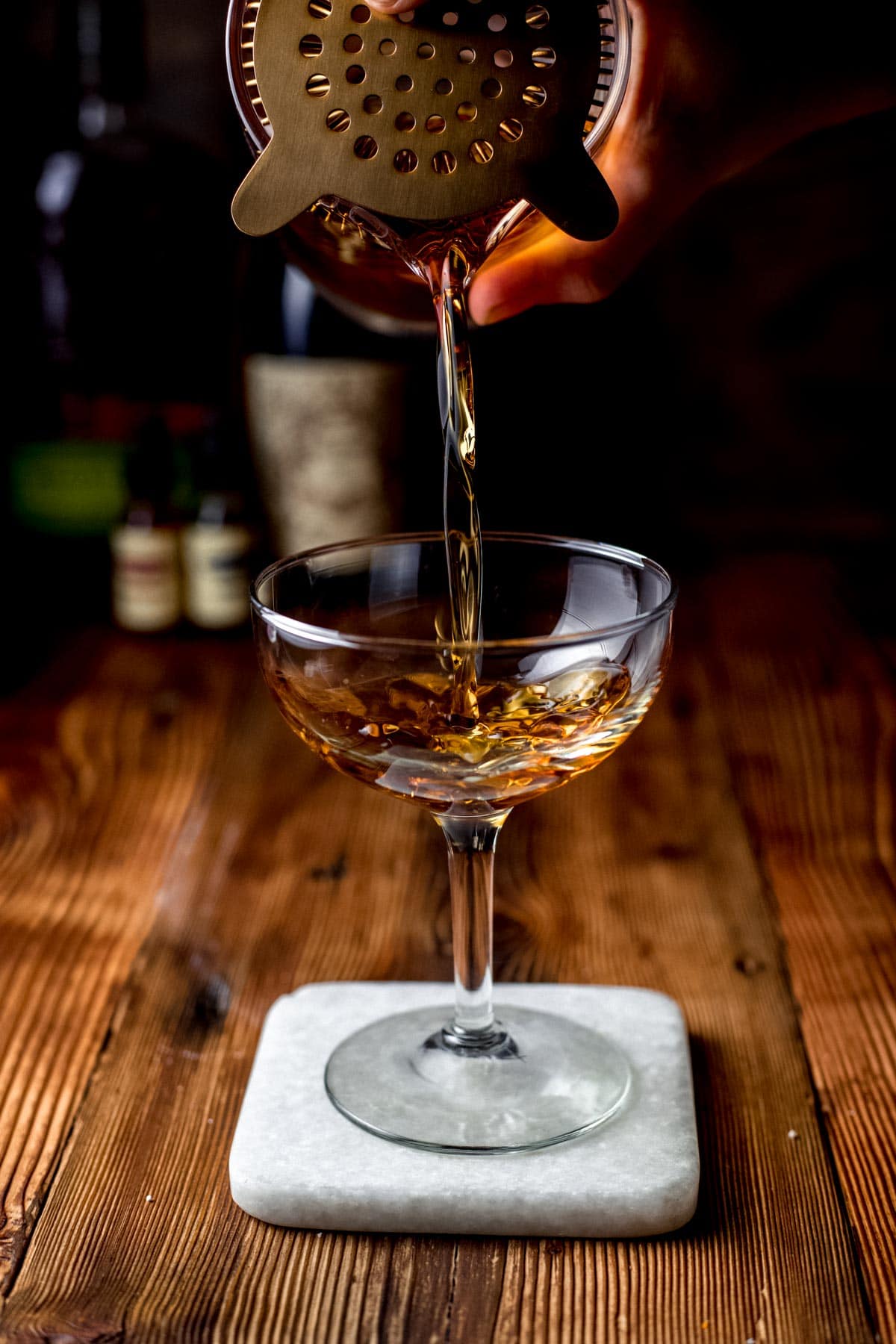 Manhattan Cocktail being strained into coupe glass